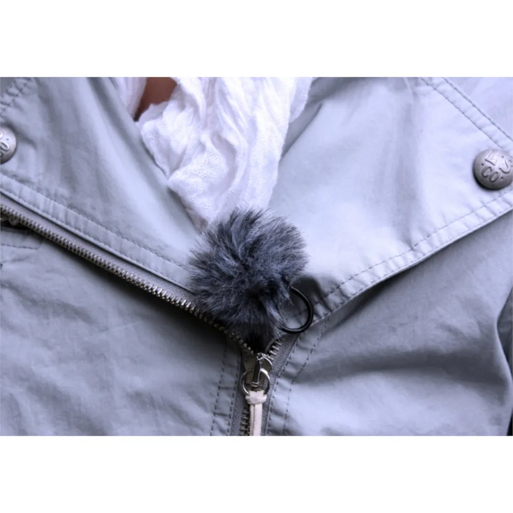 Rycote Lavalier Windjammer Fur Windscreen: A gray Lavalier Windjammer on a lav clipped to a jacket.