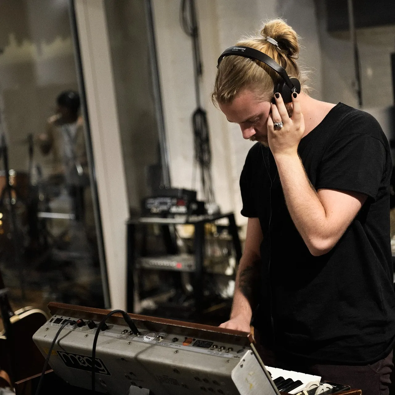 Sennheiser HD 25 Light On-Ear Headphones: A musician in a studio holding the HD 25 Light to one ear.