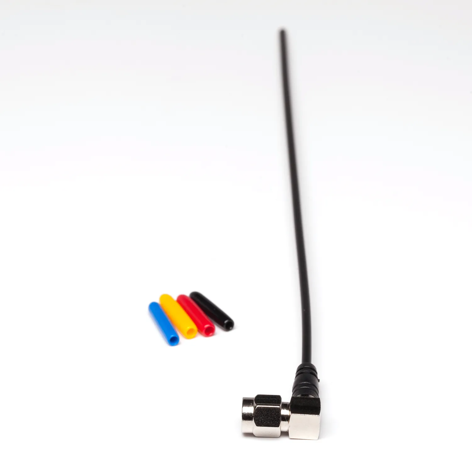 Sound Devices A-SMAR Right Angle SMA Flex Antenna, a black flexible whip with a right-angle SMA connector, shown beside four colored caps.