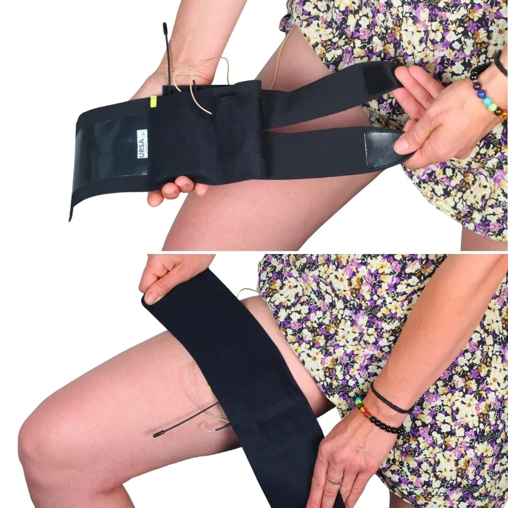 URSA Thigh Strap in black held open on the lap to show its two split ends and pouch, then wrapped around the thigh under a floral skirt.